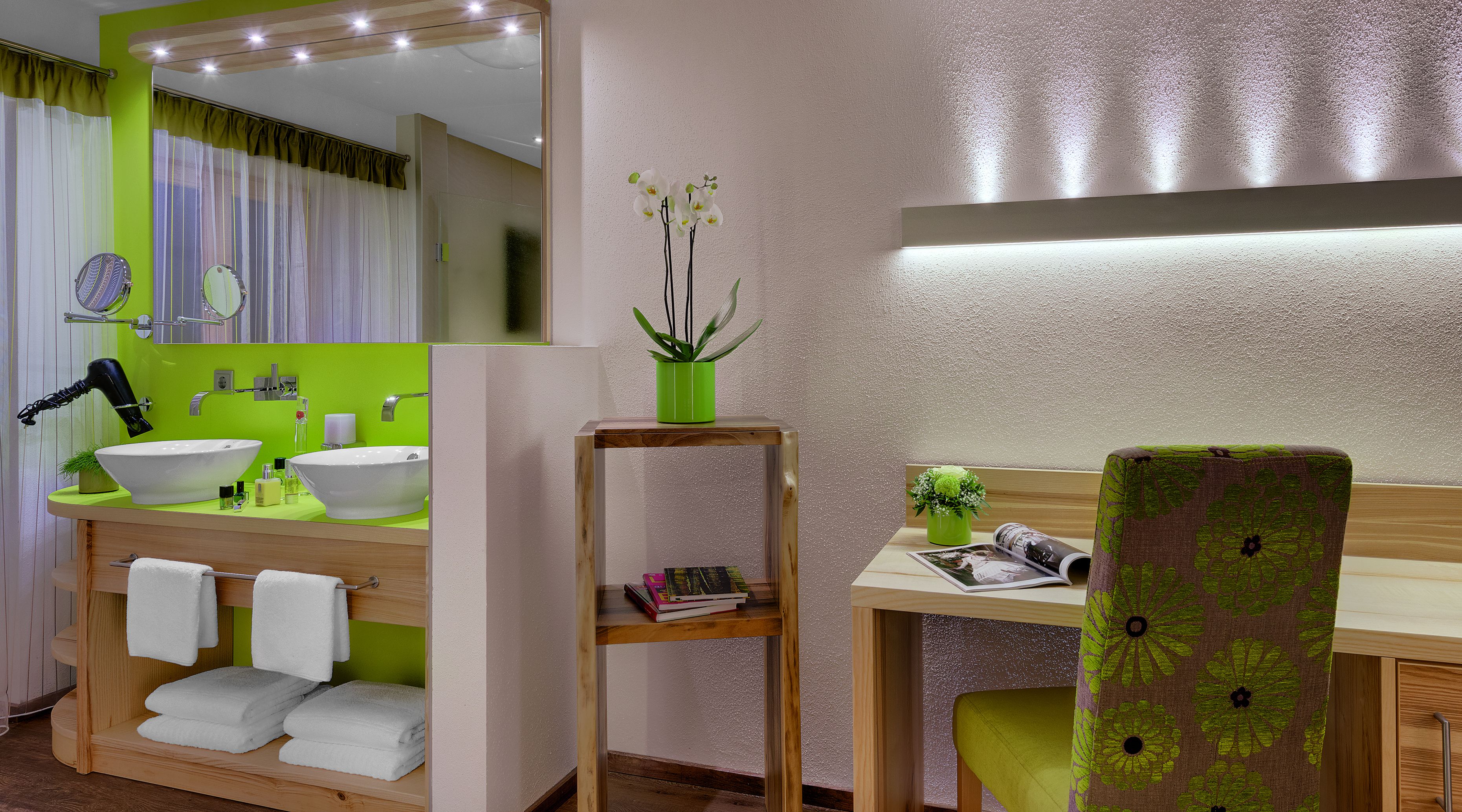 Un bagno moderno con un grande specchio, un lavabo e una toeletta con una sedia. Ci sono asciugamani e una piccola pianta sulla toeletta.