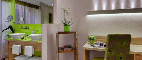 Un bagno moderno con un grande specchio, un lavabo e una toeletta con una sedia. Ci sono asciugamani e una piccola pianta sulla toeletta.