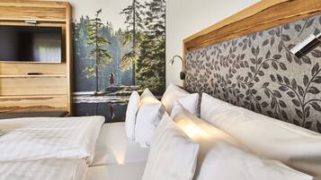 Un dormitorio con una cama, un televisor montado en un panel de madera y un mural de un bosque en la pared.