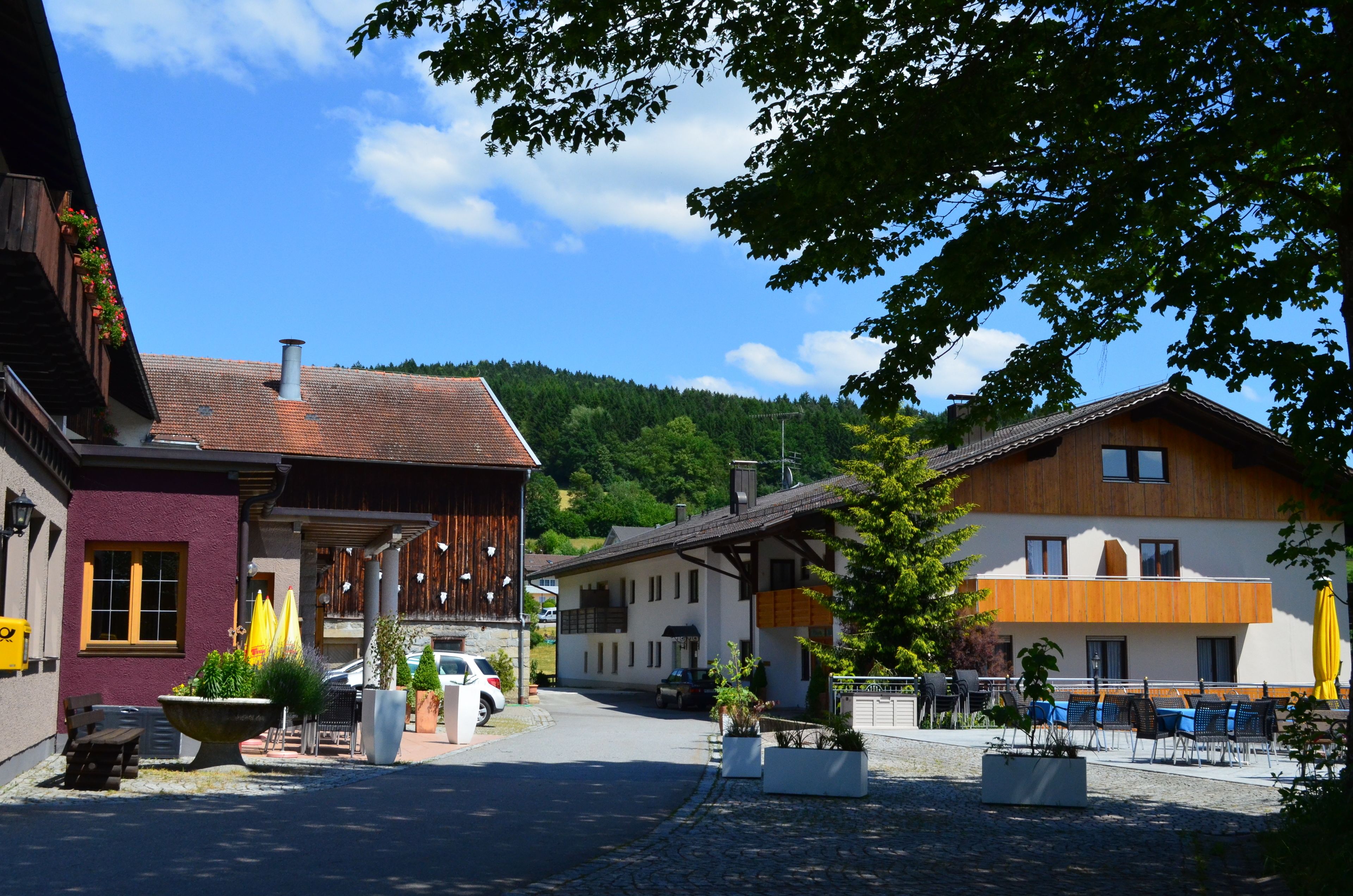 A traditional European village with wooden buildings, outdoor seating, and a clear sky.