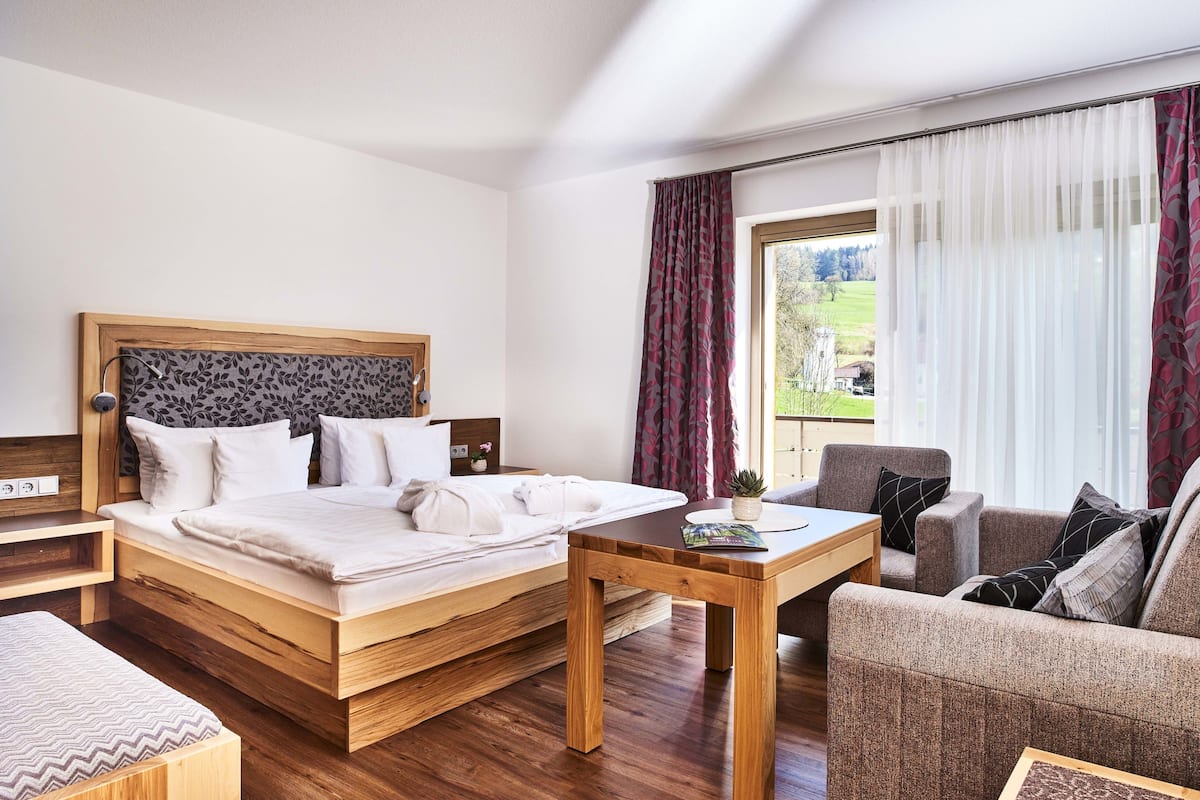 Een hotelkamer met een houten bed, nachtkastje, tafel en een bank.