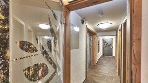 Un pasillo con suelo de madera, paredes de vidrio con diseños reflectantes e iluminación empotrada.