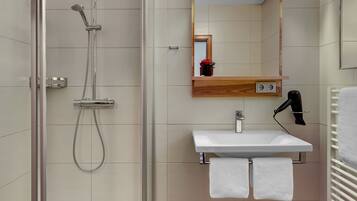Une salle de bain moderne avec une douche à parois de verre, un meuble-lavabo avec un miroir et un porte-serviettes.