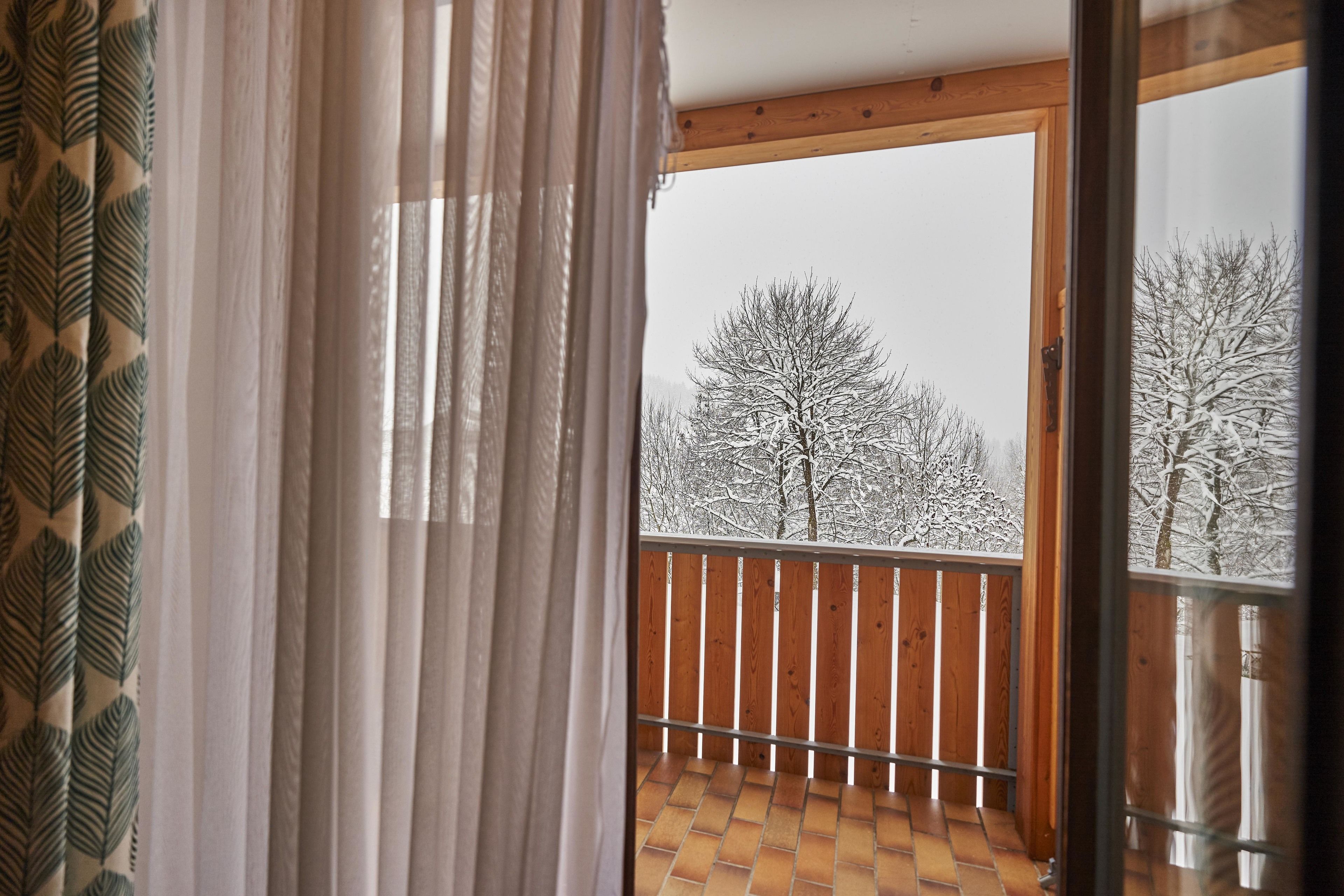 Un balcó amb barana de fusta i vista a arbres coberts de neu.