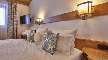 Habitación de hotel con una cama grande, dos lámparas adosadas a la pared, un televisor de pantalla plana y un cabecero de madera.