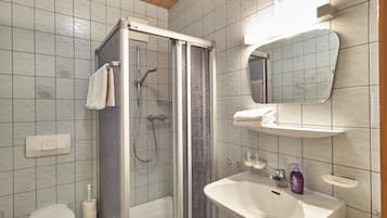 A bathroom with a shower, toilet, sink, and mirror.