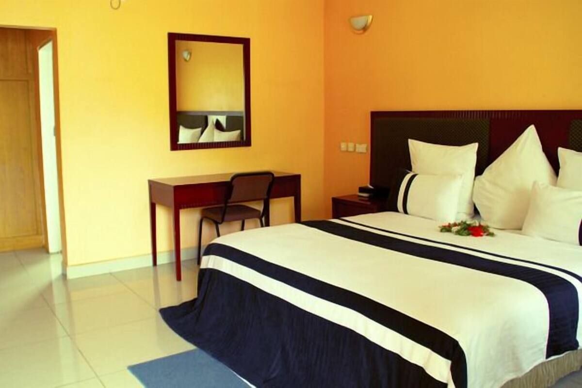 A hotel room with a large bed, a desk, and a chair.