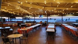 An outdoor dining area with tables and chairs, a bar, and a view of the sea. - Dampier Mermaid Hotel Karratha (Dampier)