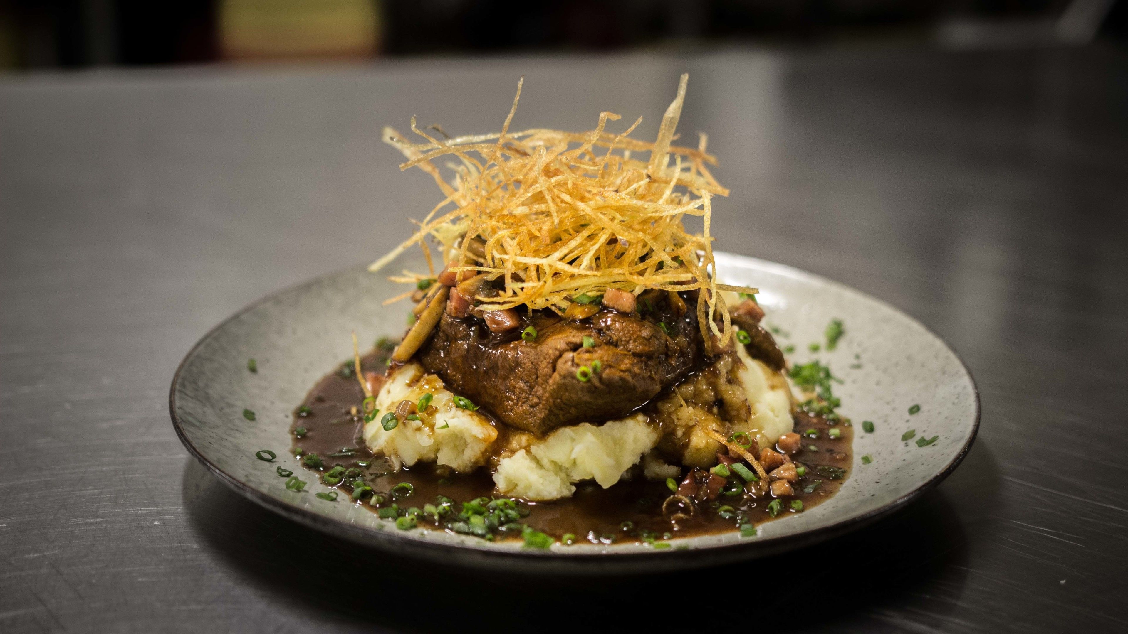 A plate of food with mashed potatoes, a beef patty, and a garnish of fried onions.
