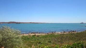 Un paisaje costero con cielo despejado, una playa arenosa y un litoral rocoso.