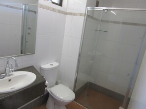 Un baño con lavabo, inodoro y ducha con mampara de vidrio.
