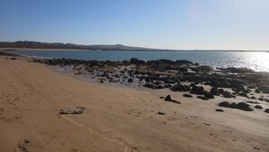 Una playa con costa rocosa y cielo despejado.
