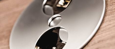 A metallic, oval-shaped object with a reflective surface, possibly a part of a piece of furniture or equipment, on a wooden surface.