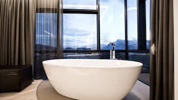 Un bagno moderno con una vasca freestanding, ampie finestre e vista sulle montagne.