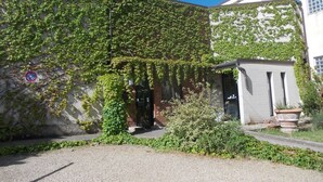 Een gebouw met muurranken, een grindpad en een kleine inrit met een deur.