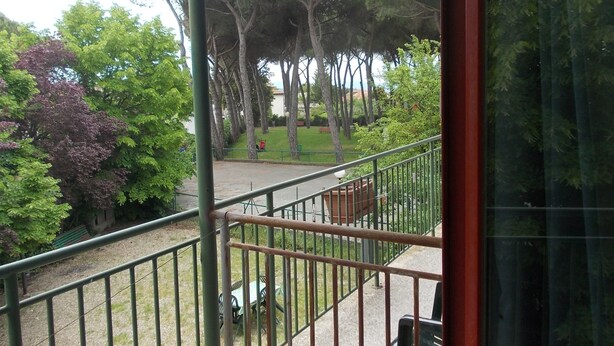 Een balkon met uitzicht op een park, inclusief bomen en gazon.