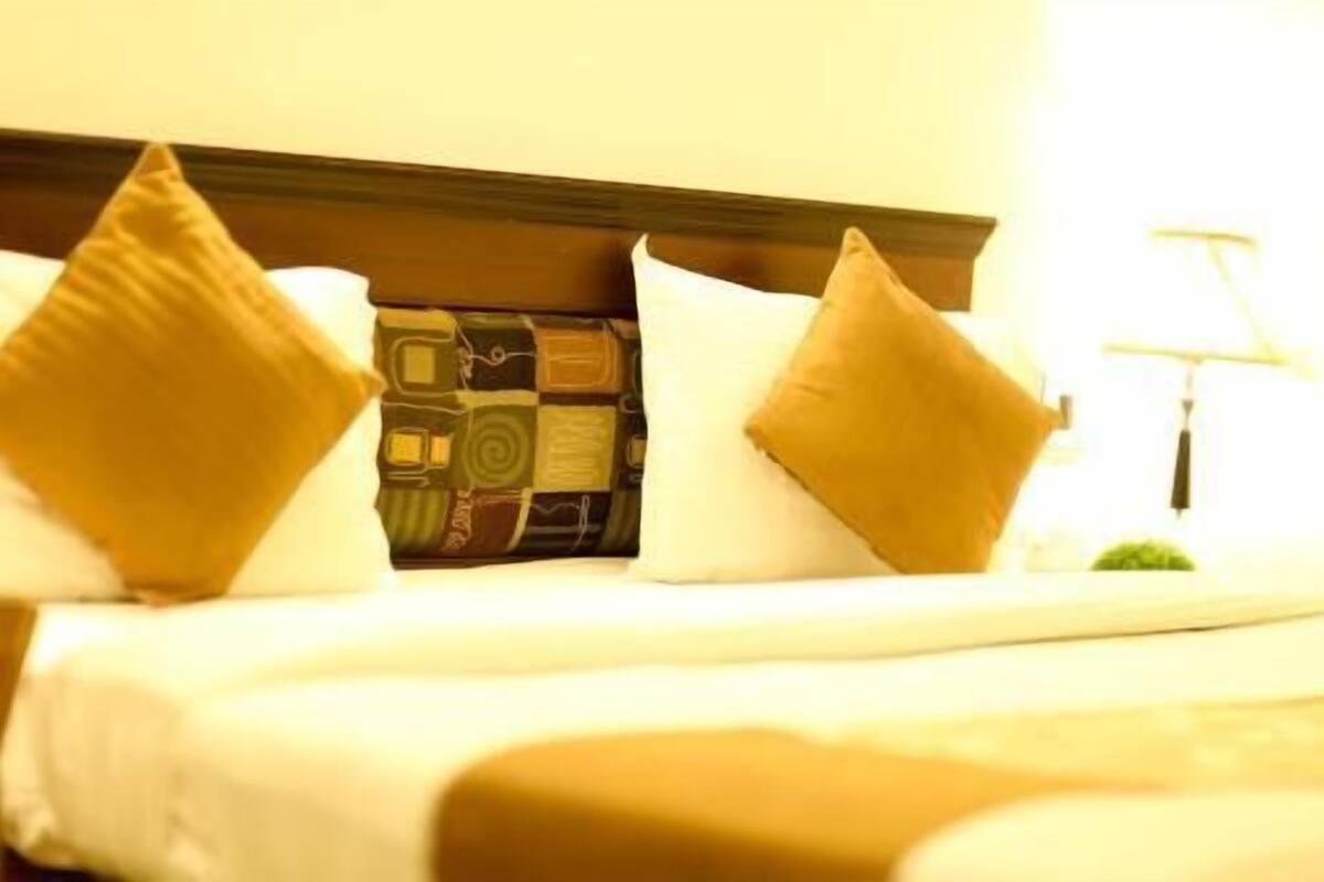 Ein Bett mit einem gemusterten Kopfteil, zwei Kissen und einer Nachttischlampe.