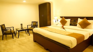 Une chambre d’hôtel avec un grand lit, un bureau, deux chaises et une armoire.