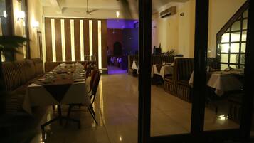 A dining area with a long table set for a meal, surrounded by cushioned seating.