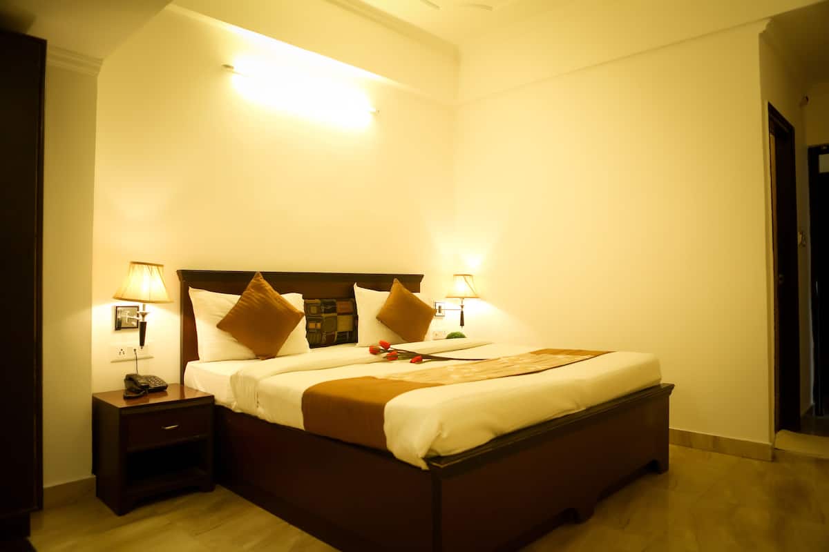 Ein Hotelzimmer mit einem großen Bett, zwei Nachttischen mit Lampen, einem Holz-Kopfteil und einem Beistelltisch mit Telefon.