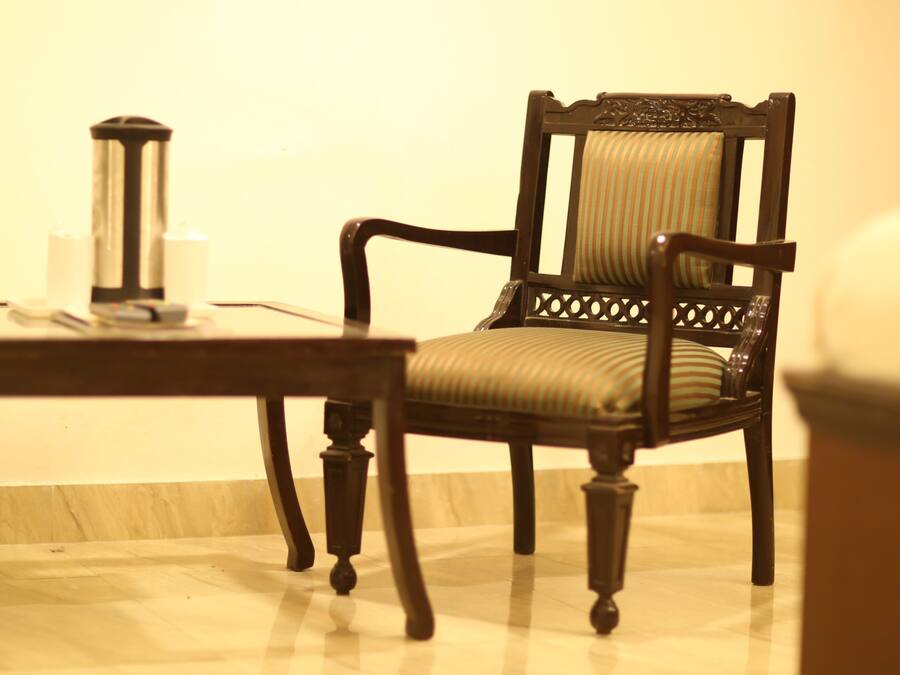 A wooden chair with a cushioned seat and backrest, positioned next to a small table with a cylindrical object on it.