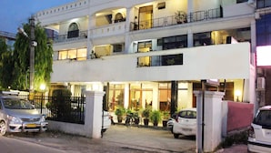 Un hôtel à plusieurs étages, doté d’une façade blanche, de balcons et de plantes en pot.