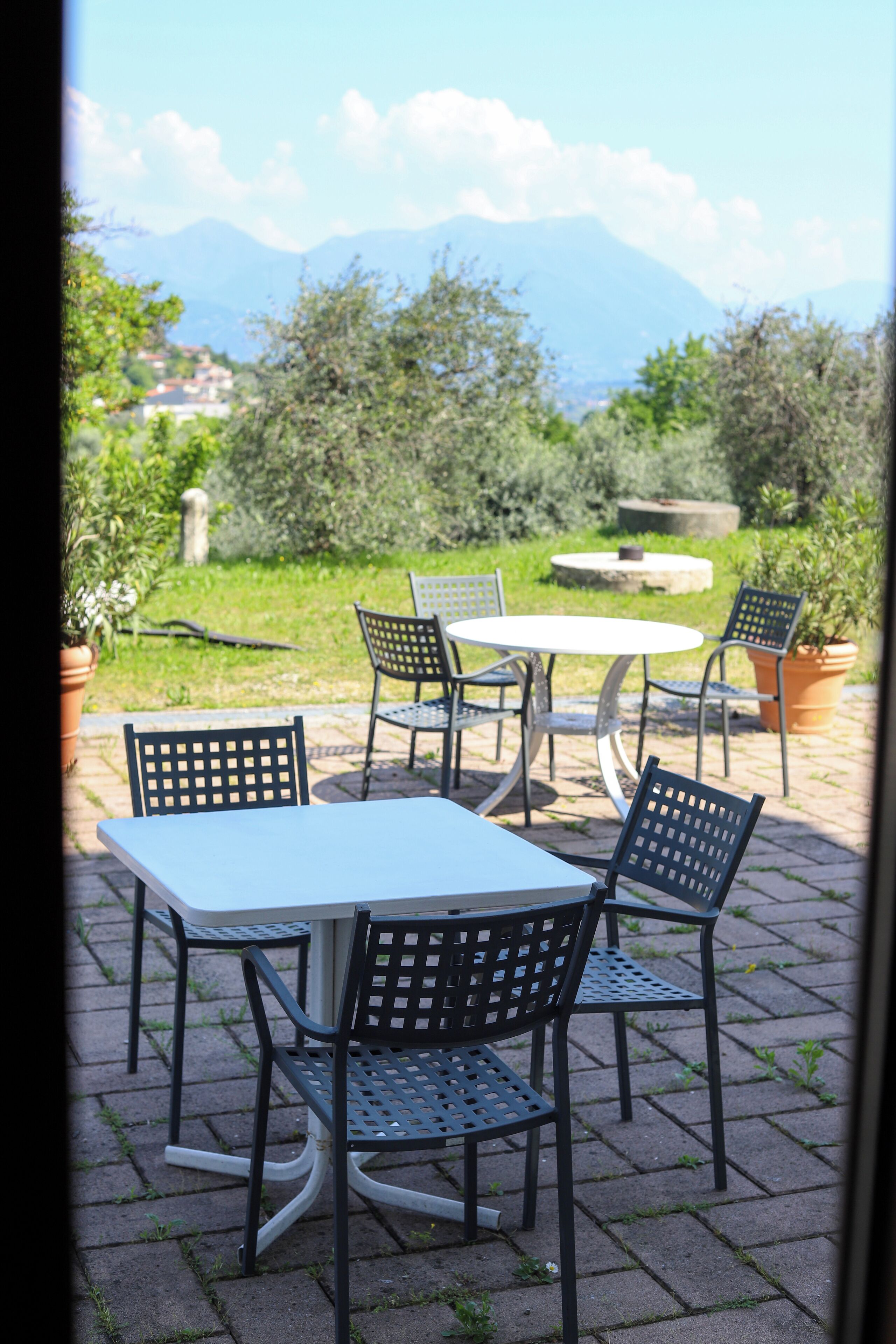An outdoor patio with a table and chairs, a potted plant, and a view of mountains.