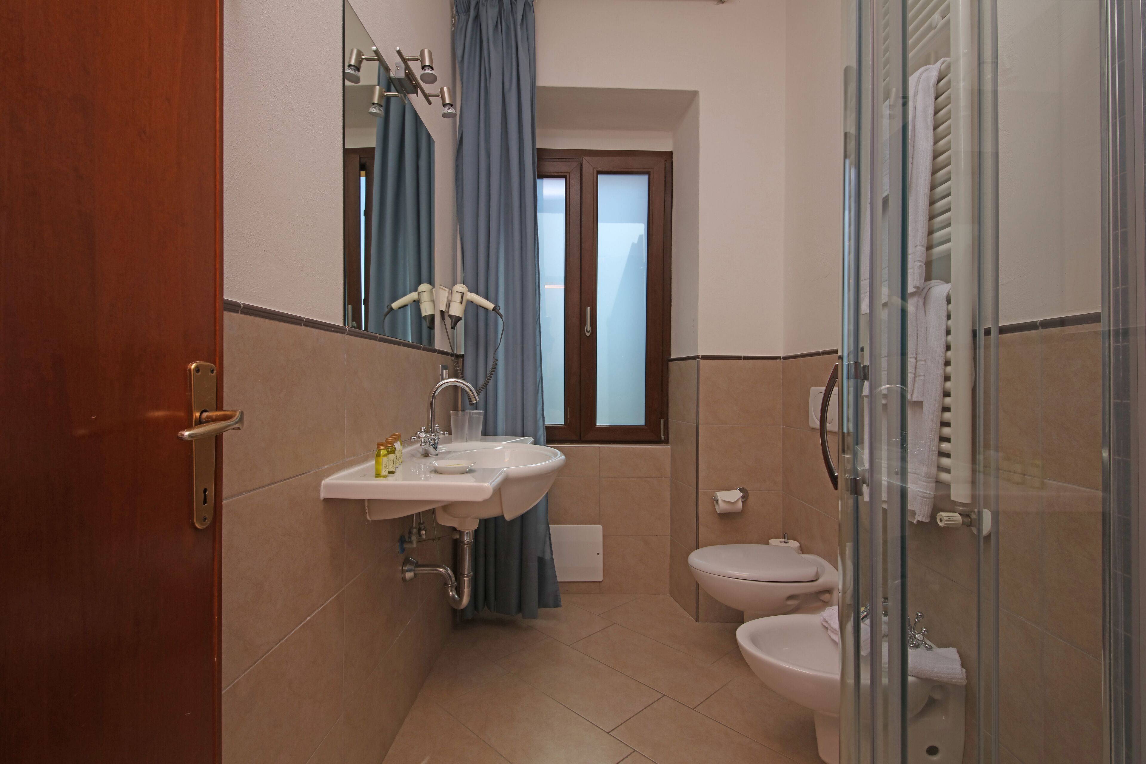 Un bagno con lavandino, specchio e due servizi igienici.