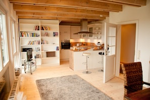 A spacious kitchen with wooden beams, white cabinetry, and a central island with bar stools. - urlaubsart - Guldehof (Stoltebuell)