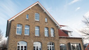 A brick building with multiple windows and a red roof. - urlaubsart - Am Rathaus (Kappeln)