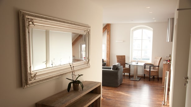 A spacious room with a large mirror, wooden bench, and a dining area with chairs and a table. - urlaubsart - Am Rathaus (Kappeln)