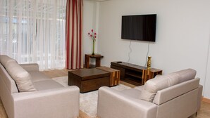 A modern living room with a sofa set, a coffee table, and a flat-screen TV mounted on the wall. - Nairobi Executive Suites (Syokimau)