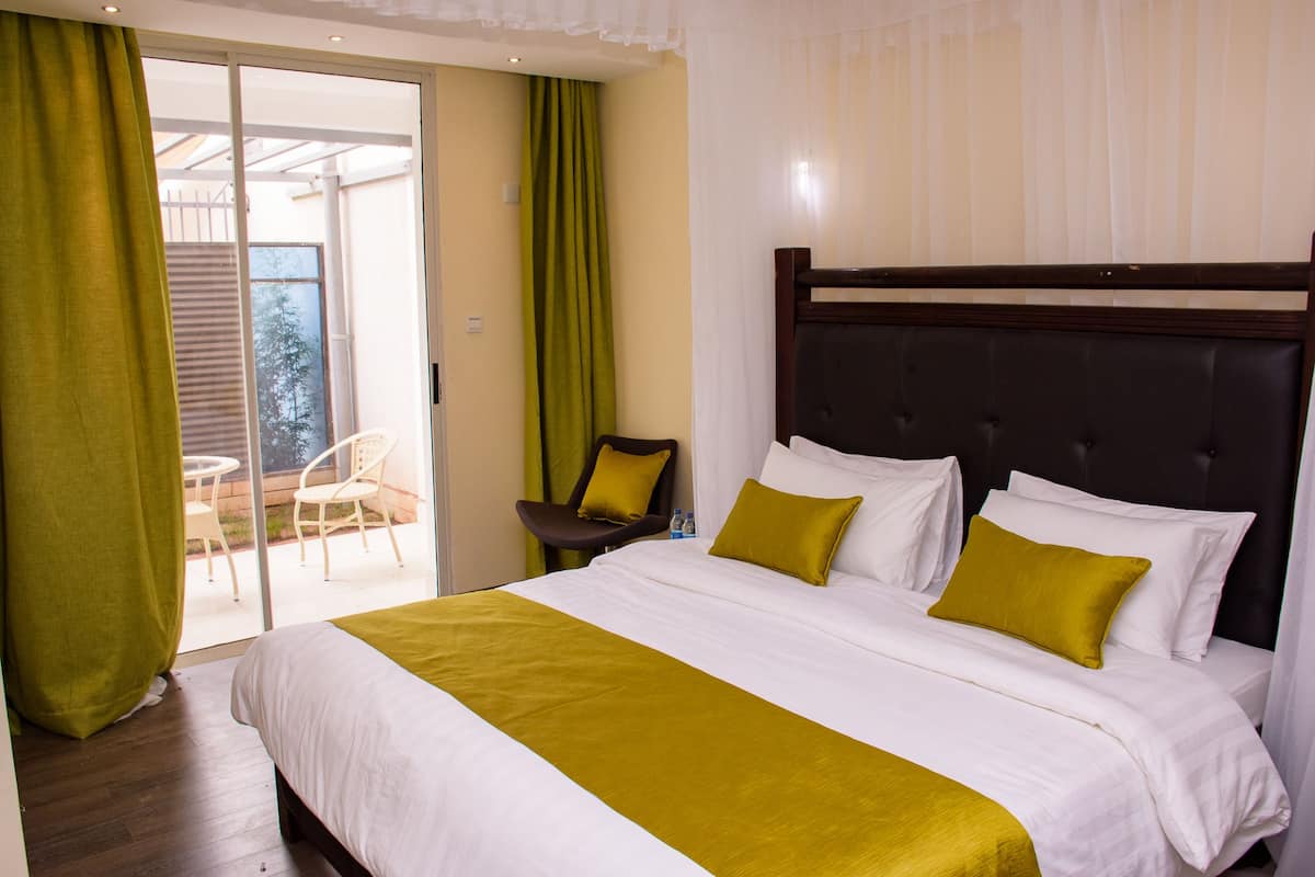 Ein Hotelzimmer mit einem großen Bett, einem Sessel, einem kleinen Tisch und einer Schiebetür zum Balkon.
