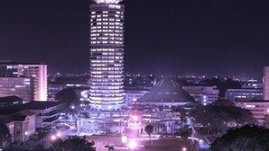 A tall, illuminated hotel with a distinctive top and multiple floors. - Nairobi Executive Suites (Syokimau)