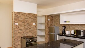 A modern kitchen with a granite countertop, stainless steel appliances, and a brick-patterned backsplash. - Nairobi Executive Suites (Syokimau)