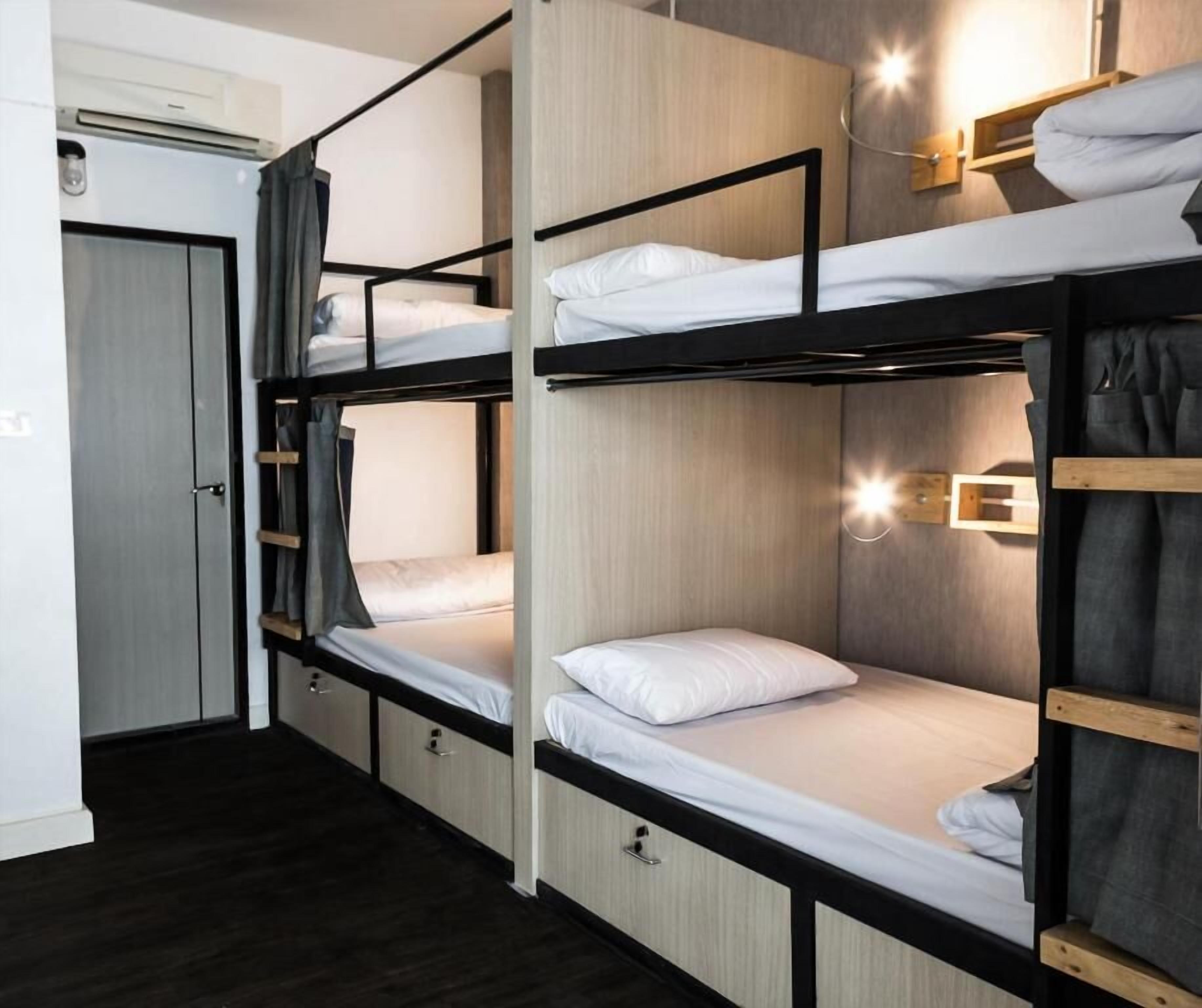 Habitación con literas, suelo de madera, una puerta y un aplique de pared.