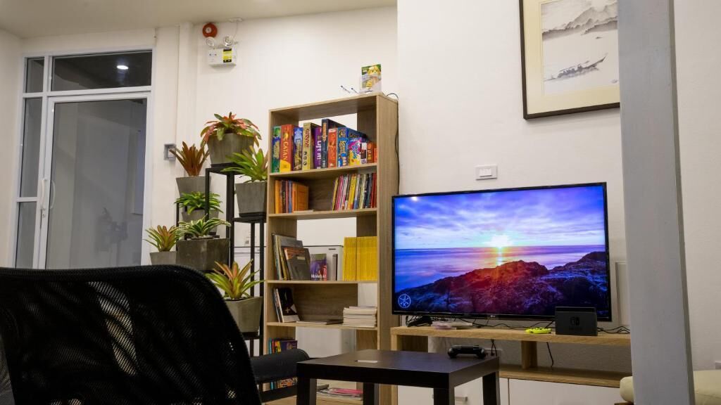A living room with a bookshelf, a flat-screen TV, and a desk.