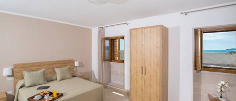 Un dormitorio con cama, mesita de noche, armario de madera y ventana con vistas.