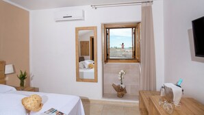 Ett hotellrum med en säng, ett badrum med dusch, ett fönster med utsikt och en tv på väggen.