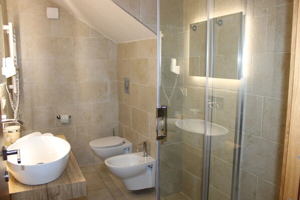 A modern bathroom with a large vessel sink, a bidet, a toilet, and a glass-enclosed shower area. - Hotel Punta San Francesco (Vieste)