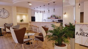 Zona de bar moderna con un reloj, taburetes y una planta en maceta.