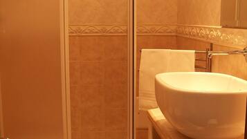 A bathroom with a glass-enclosed shower, a white sink, and a toilet.