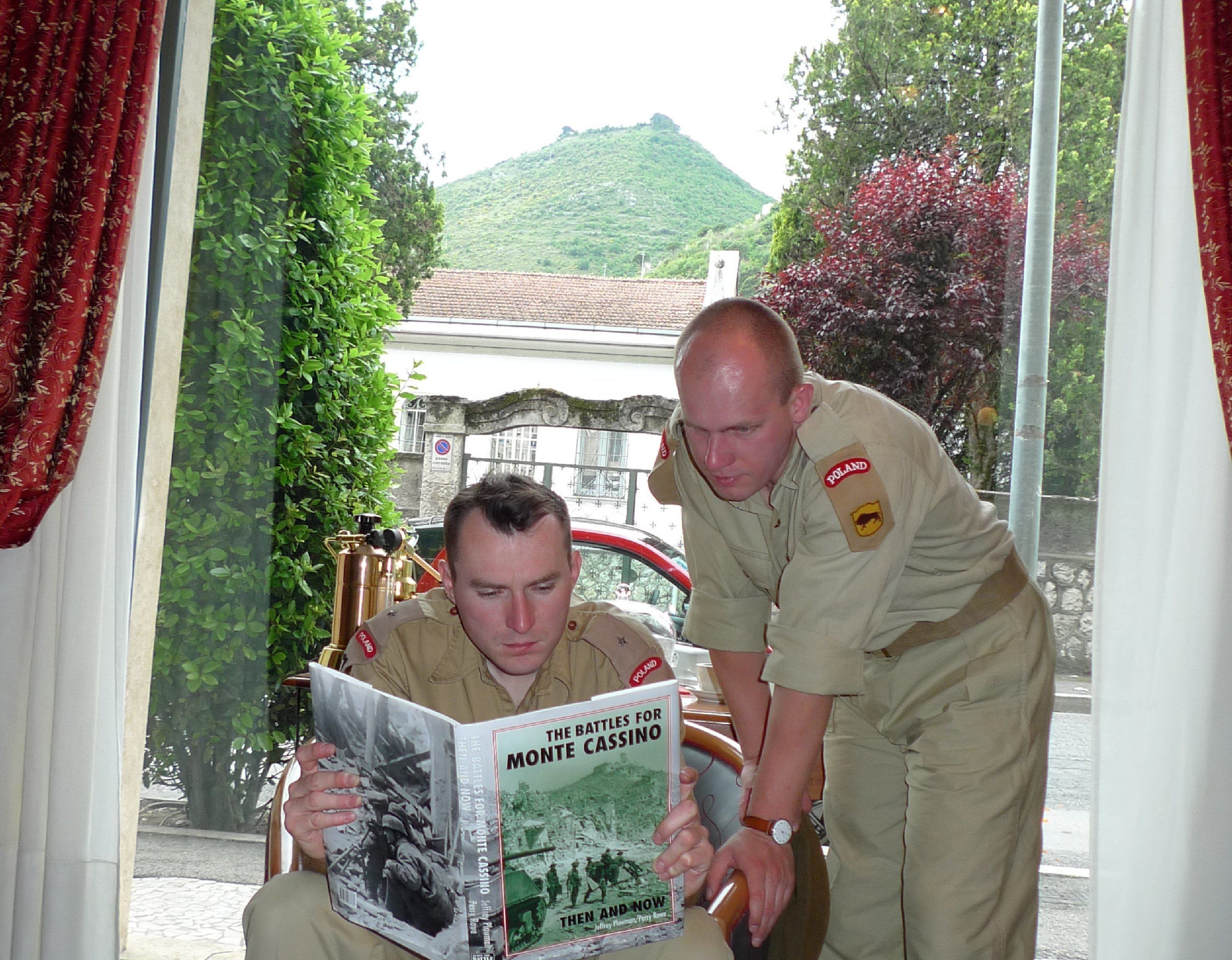 Twee personen zitten aan een tafel met een boek getiteld 'The Battles for Monte Cassino'.