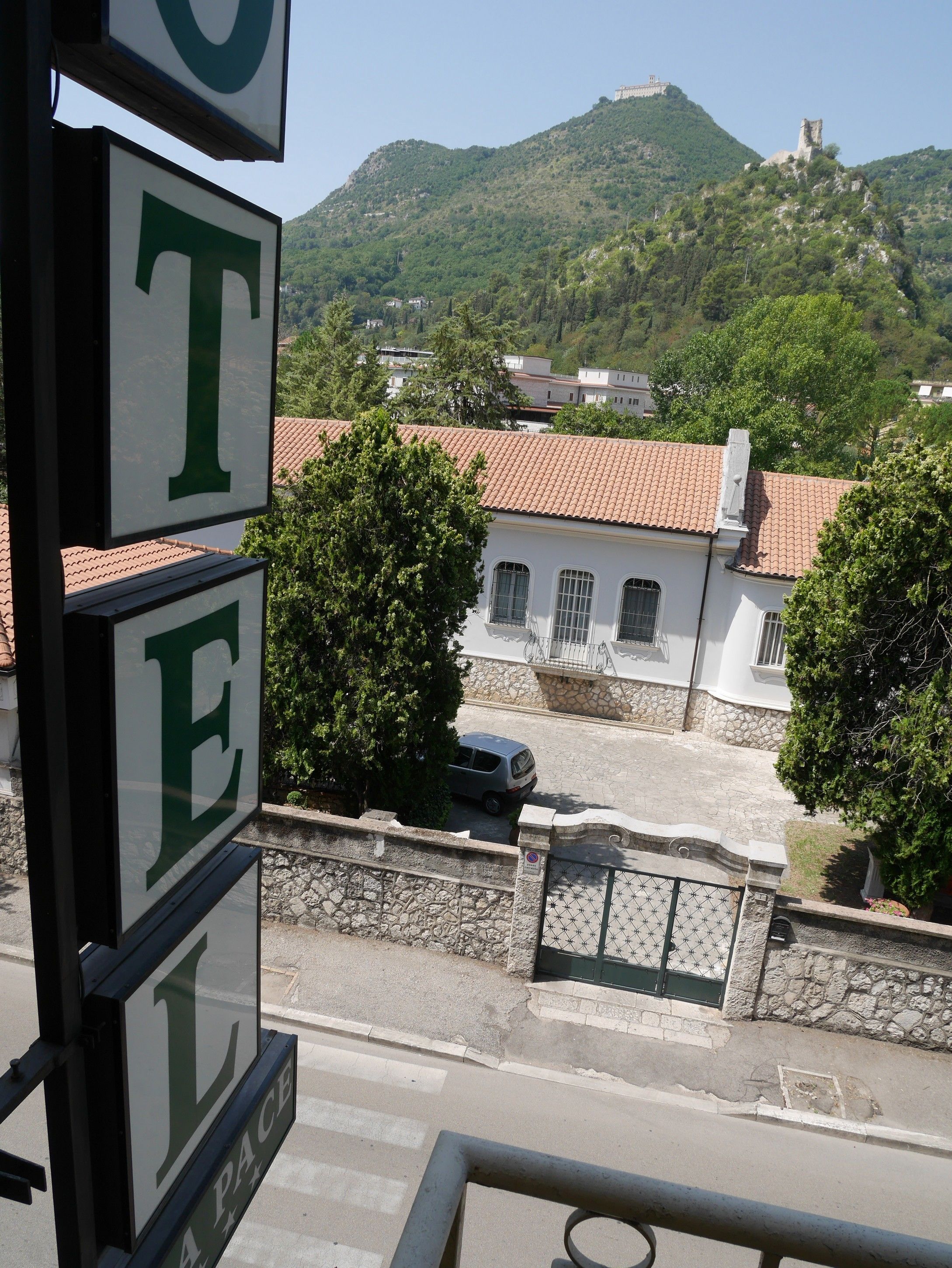 A hotel sign with a view of a mountain and traditional buildings in the background.
