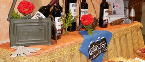 A table with wine bottles, a flower, and cheese.