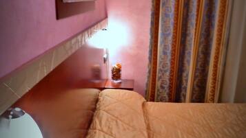 Una habitación de hotel con una cama, una mesita de noche con una lámpara, un ratón de ordenador y un cuadro en la pared.