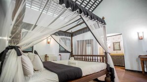A bed with a canopy, a wooden headboard, and a white wall with a window.