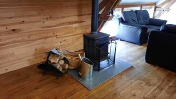 A cozy room with a wood-burning stove, a sofa, and a log storage area.