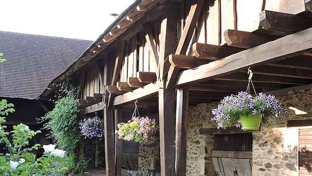 A rustic stone building with wooden beams and hanging flower baskets. - The Alpaca B&B (Chalais)