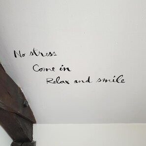 Una pared con texto escrito a mano que dice: "Sin estrés, entra, relájate y sonríe." 